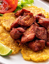Fried pork carne frita over golden tostones with lime